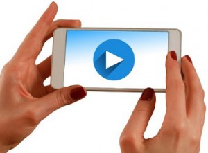 Hands holding a mobile phone with a video on the screen