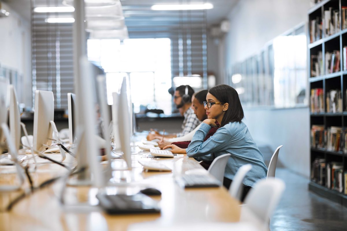 Shot of a group of university students working on computers in the library at campus.